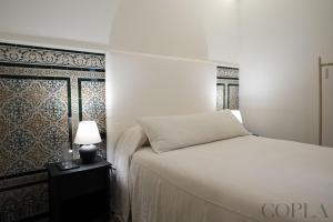 a bedroom with a white bed and a lamp on a table at Cool&Modern Apt para 4pax en el centro de Sevilla in Seville