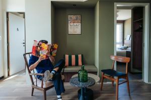 człowiek siedzący na krześle czytający książkę w obiekcie JOST Hostel Montpellier Centre St Roch w Montpellier