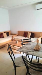 a living room with a table and chairs and a couch at Monastir: superbe appartement neuf (2020) in Monastir