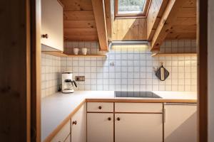 una pequeña cocina con armarios blancos y techos de madera. en Apartment Ruiel, en Santa Cristina Valgardena