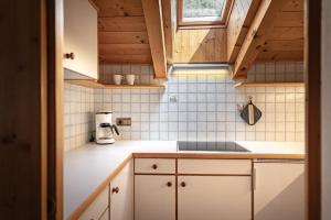 a small kitchen with white cabinets and wooden ceilings at Apartment Ruiel in Santa Cristina Gherdëina