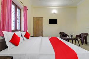 a bedroom with a large white bed with red pillows at Balindira Guest House in Dehradun