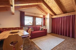 sala de estar con sofá rojo y mesa de madera en Apartment Ruiel, en Santa Cristina Valgardena