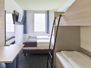 a small room with two bunk beds and a window at B&B Hotel Köln-Airport in Cologne