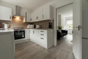 Una cocina con gabinetes blancos y una sala de estar. en Glenisla House, en Glasgow