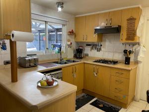 una cocina con armarios de madera y un bol de fruta en la barra en Casa del Arce en Puerto Varas