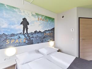 a bedroom with a poster of a person on a mountain at B&B Hotel Köln-Airport in Cologne