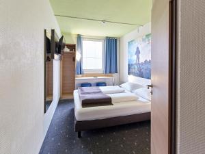 a bedroom with two beds and a window at B&B Hotel Köln-Airport in Cologne