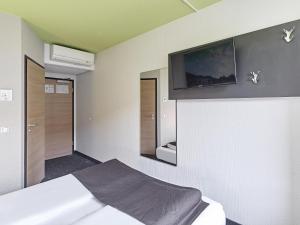 a bedroom with a bed and a tv on the wall at B&B Hotel Köln-Airport in Cologne