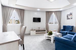 a living room with two blue chairs and a tv at Hotel Mamora Kénitra in Kenitra