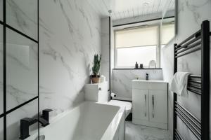 a white bathroom with a tub and a sink at Shaw Apartment in Glasgow