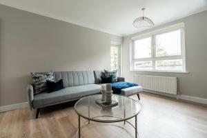 - un salon avec un canapé et une table en verre dans l'établissement Shaw Apartment, à Glasgow