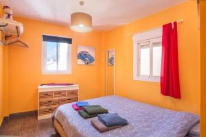 a bedroom with orange walls and a bed with red curtains at Apartment Calle Larga in Fuengirola