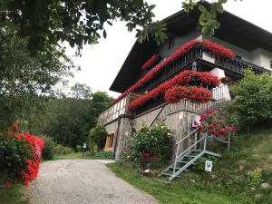 een gebouw met rode bloemen aan de zijkant bij Pension Alpenblick in Vipiteno