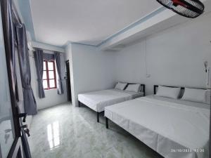 a white room with two beds and a window at Tua's Homestay in Mai Châu