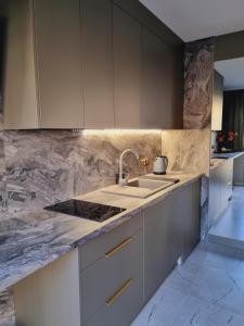 a kitchen with white cabinets and a sink at Apartament Jacuzzi in Kraków