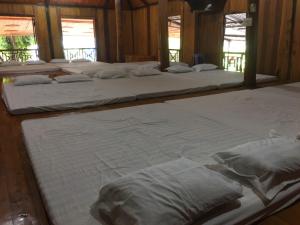 a row of white beds in a room at Tua's Homestay in Mai Châu