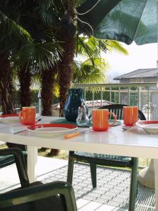 una mesa blanca con platos rojos y utensilios. en Appartamenti Girasole, en Cannobio