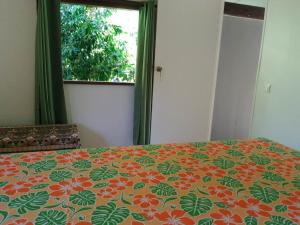 - une chambre dotée d'un lit avec un couvre-lit orange et vert dans l'établissement Fare Mihimana, à Vaïare