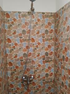 a shower in a bathroom with a stone wall at Fare Mihimana in Vaïare