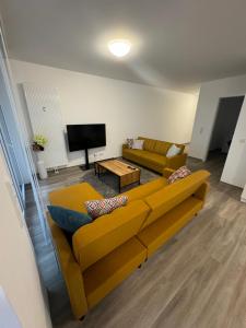 a living room with a yellow couch and a flat screen tv at to be apartments Deluxe-Suites in Weiden