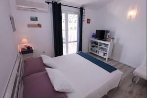 - une chambre avec un lit blanc et un canapé dans l'établissement Apartments Luka, à Rogoznica