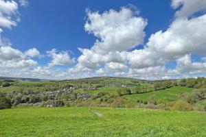 ein grünes Feld mit einer Stadt in der Ferne in der Unterkunft Apple Cottage: 19th Century Charm in Calder Valley in Luddenden Foot