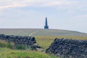 eine Steinmauer mit einem Leuchtturm im Hintergrund in der Unterkunft Apple Cottage: 19th Century Charm in Calder Valley in Luddenden Foot
