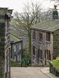 ein altes Backsteinhaus mit Kamin darüber in der Unterkunft Apple Cottage: 19th Century Charm in Calder Valley in Luddenden Foot
