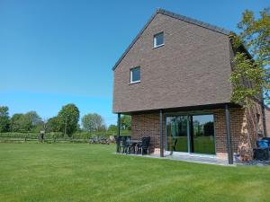 een stenen huis met glazen schuifdeuren op een veld bij Côté Jardin 