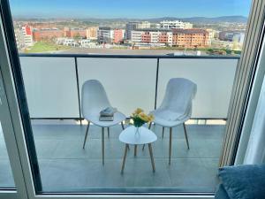 2 chaises et une table avec un vase de fleurs sur le balcon dans l'établissement Apto HUCA. Parking/WIFI incluido, à Oviedo