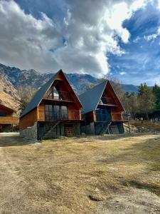 a large wooden house with mountains in the background at Cottage Paradise in Stepantsminda