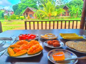 a table with plates of fruits and vegetables on it at Sigiriya Nature Resort in Sigiriya