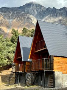 una cabaña de madera con montañas al fondo en Cottage Paradise, en Kazbegi