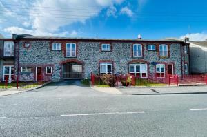 a brick building with a red fence in front of it at Lovely apartment overlooking the harbour and bay in Ardglass
