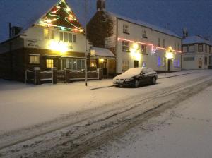 a snow covered street with a car parked in front of a building at Oak house hotel in Wellingborough