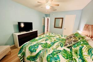a bedroom with a bed with a leafy comforter and a television at Large 2BR Across From Beach & 5 Min From Hangout in Gulf Shores