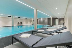 a large swimming pool with two tables and a swimming pool at BSW Hotel Ahlbeck in Ahlbeck