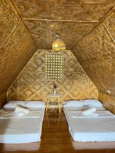 um quarto com duas camas e uma mesa em Camiguin Blue Lagoon Cottages em Mahinog