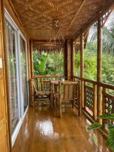 Camiguin Blue Lagoon Cottages في Mahinog: شرفة منزل مع طاولة وكراسي