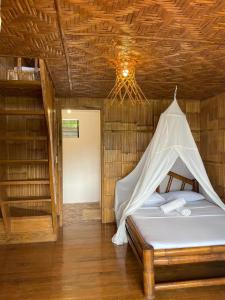 Camiguin Blue Lagoon Cottages في Mahinog: غرفة نوم بسرير مع ناموسية