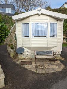 a small house with a bench in front of it at The Ocean Pearl caravan number 50 situated on the Cove holiday park in Southwell