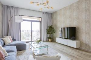 a living room with a couch and a tv at Nasma Luxury Stays - Fabulous Apartment With Balcony Near MJL's Souk in Dubai