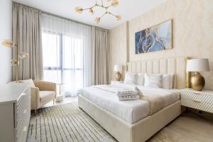 a white bedroom with a large bed and a chandelier at Nasma Luxury Stays - Fabulous Apartment With Balcony Near MJL's Souk in Dubai