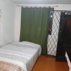 ein Schlafzimmer mit einem Bett und einem grünen Vorhang in der Unterkunft Maya Suite in Cuenca