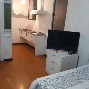 Zimmer mit einem TV auf einer Kommode mit einem Bett in der Unterkunft Maya Suite in Cuenca