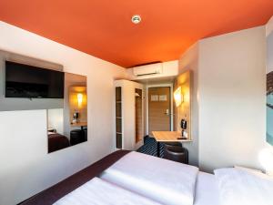 une chambre d'hôtel avec un lit au plafond orange dans l'établissement B&B Hotel Konstanz, à Constance