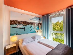 - une chambre avec un lit et une grande fenêtre dans l'établissement B&B Hotel Konstanz, à Constance