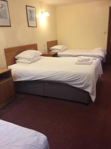 two beds in a hotel room with white sheets at Oak house hotel in Wellingborough