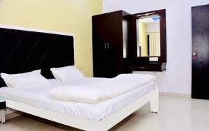 Hotel 7 Seas في Mundra: سرير أبيض في غرفة مع مرآة